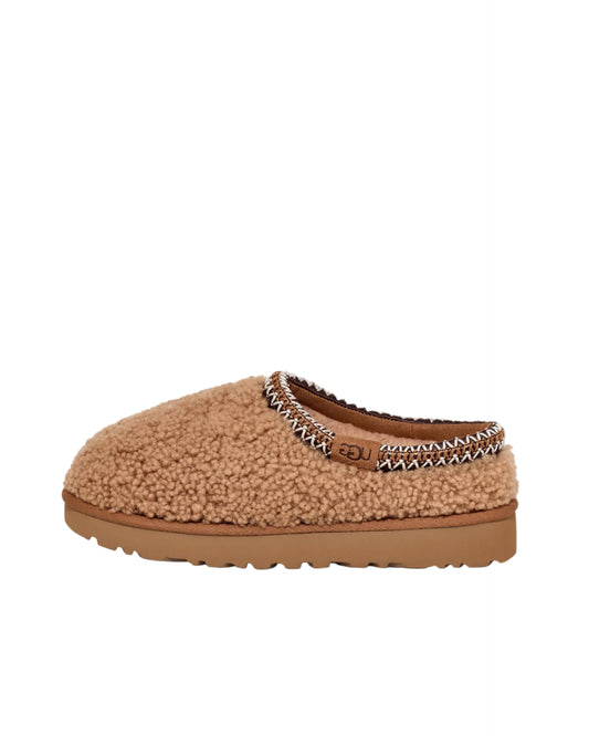 Brown UGG slipper with decorative trim on a white background