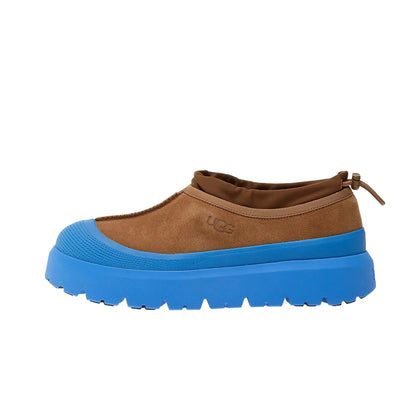 Brown slip-on shoe with blue sole on a white background