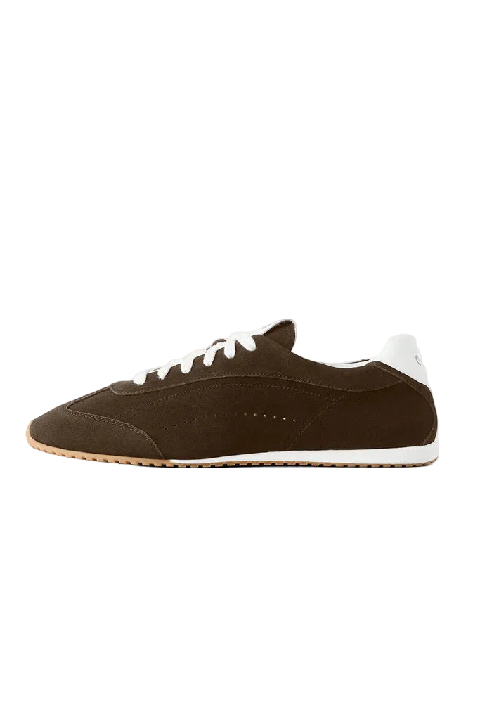 Brown sneaker with white laces on a light gray background