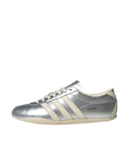 Silver Adidas sneaker with white stripes on a white background