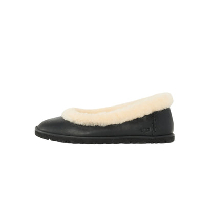 Black slip-on shoe with white fur lining on a light gray background