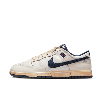 Beige sneaker with navy swoosh logo on a white background