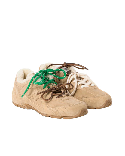 Beige sneakers with green and brown laces on a white background
