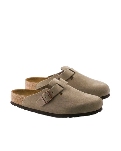 Pair of brown suede clogs with a buckle on a white background